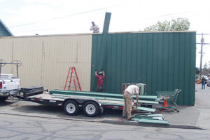 Installing salvaged metal roofing as siding at The RE Store