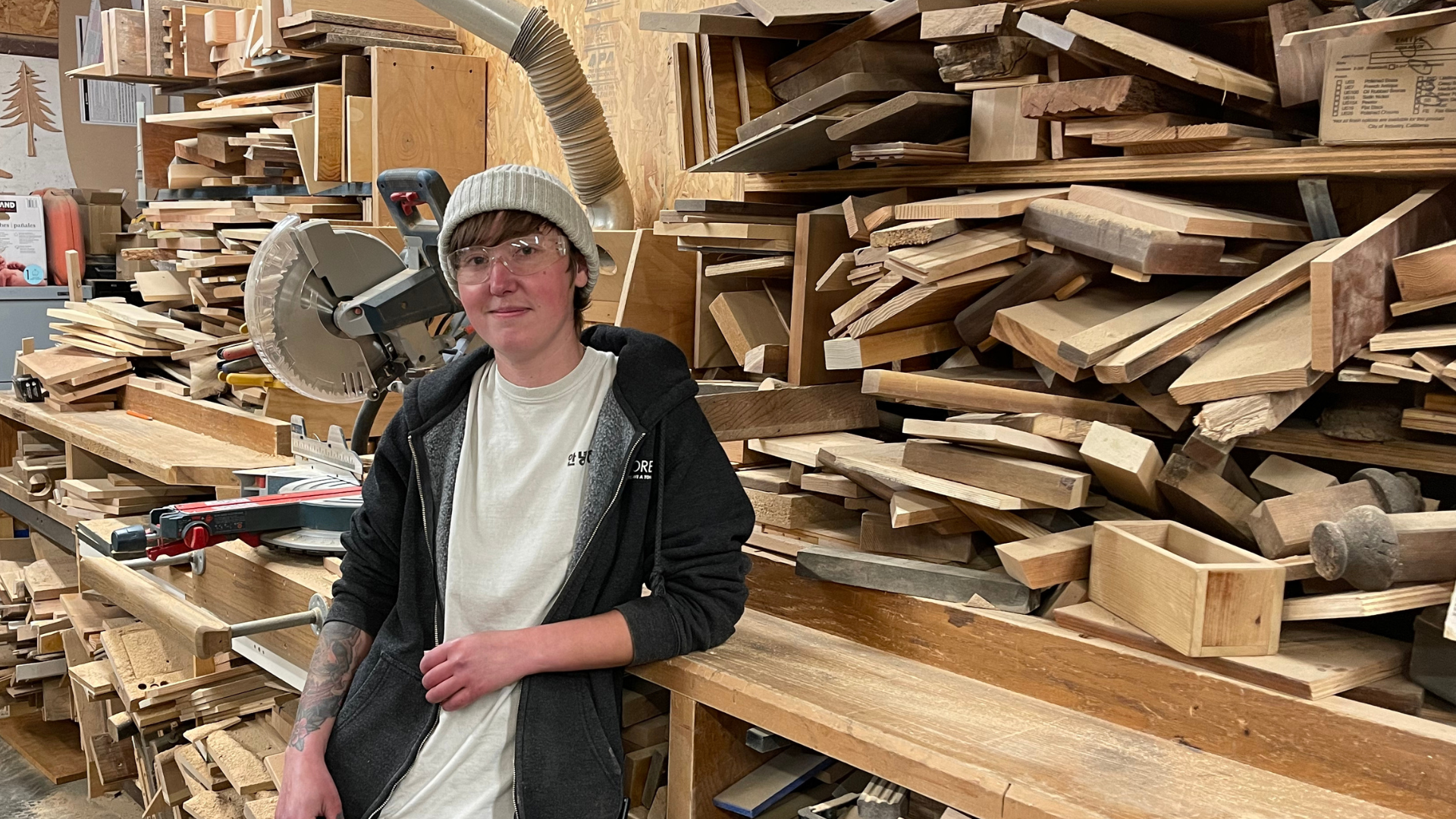 Mak leaning against a pile of cut lumber